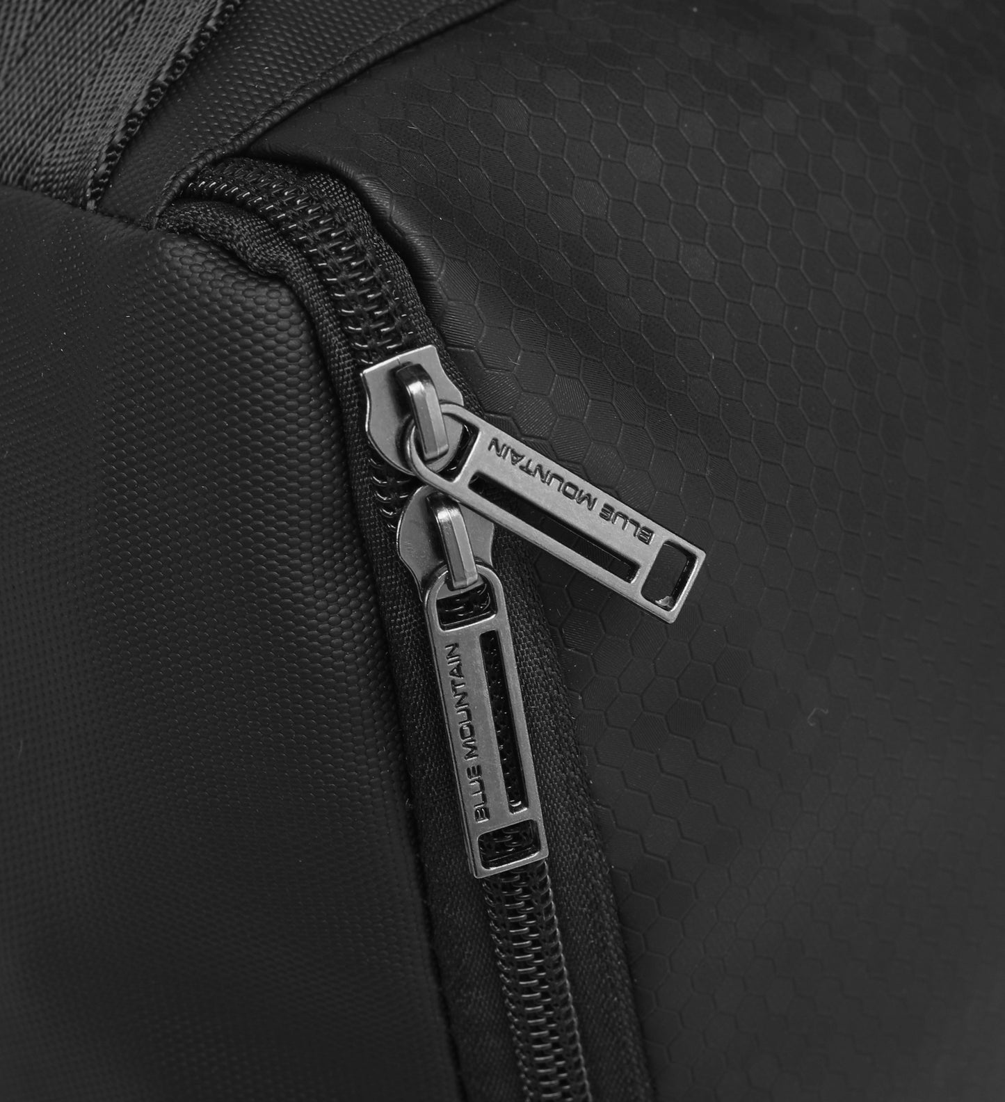 Close-up of a black backpack zipper with brand name on a dark background